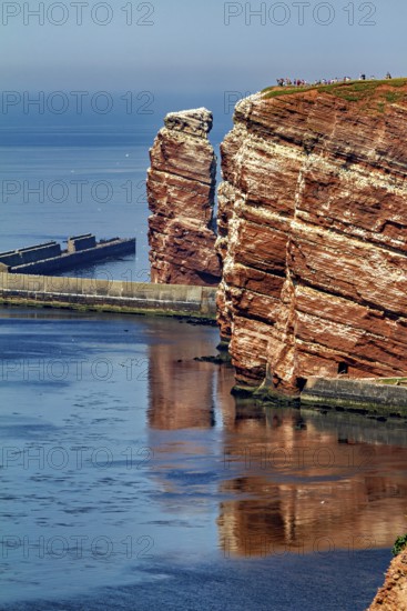 Tall red rocks rise above the sea with a protective pier, the high-seas island of Heligoland in the North Sea
