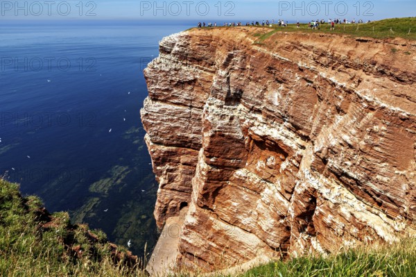 Rocky cliffs tower over the calm blue sea, the high-seas island of Heligoland in the North Sea