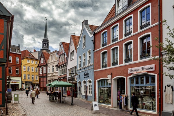 Historic street with colorful half-timbered houses and shop windows under a cloudy sky, The old town of Stade