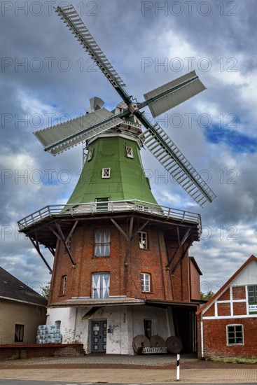 Historic brick windmill with green roof under cloudy sky, An old historic windmill near Stade