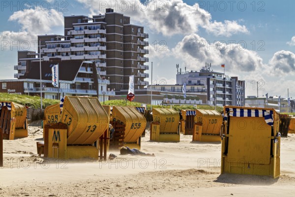 Yellow beach chairs on the beach in front of skyscrapers and a cloudy summer backdrop, beach chairs on the beach in Cuxhaven