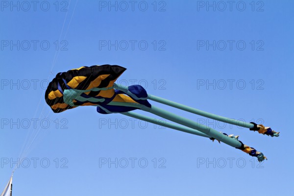 A colorful kite flies high in the blue sky in sunny conditions, a kite in the air