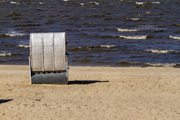 A single white beach chair stands alone on the quiet and windy beach, beach chairs on the beach in Cuxhaven