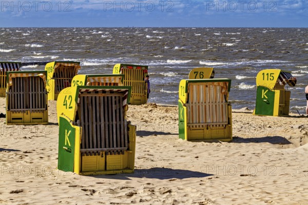 There are some beach chairs on a bright beach with a sea background under a blue sky, beach chairs on the beach in Cuxhaven
