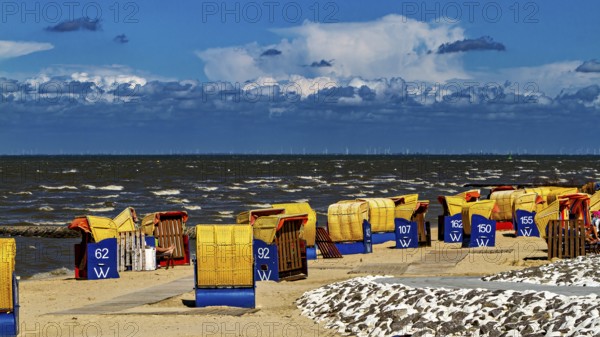 Several beach chairs along a windy beach with dramatic sky in the background, beach chairs on Cuxhaven beach