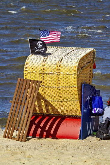 A single yellow beach chair on the beach with American and pirate flag in the wind, beach chairs on the beach in Cuxhaven