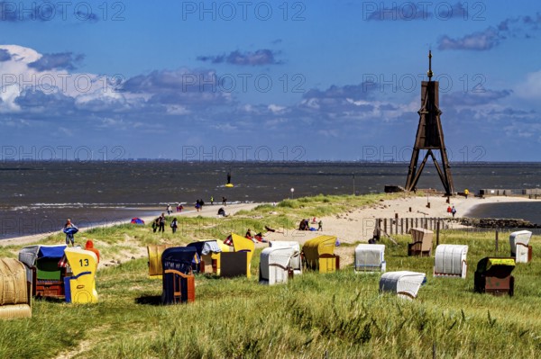 Beach on the North Sea coast with lighthouse and beach chairs under a blue sky, beach chairs on the beach in Cuxhaven