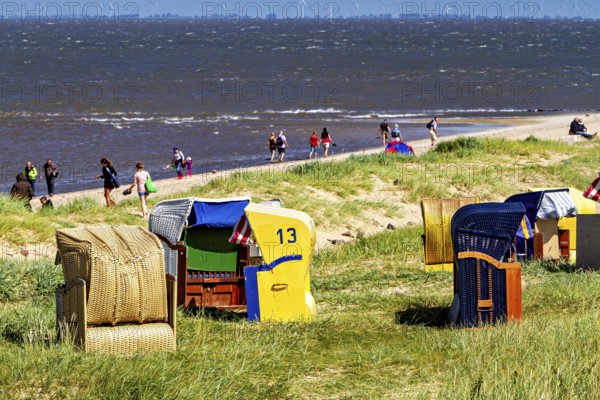 People on sandy beach with beach chairs on the coast and sea view, beach chairs on Cuxhaven beach