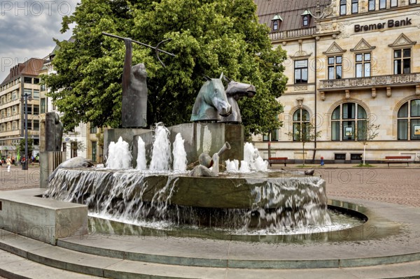 Fountain with horse sculptures and running water on a town square in front of a historic building, The center of the Hanseatic City of Bremen