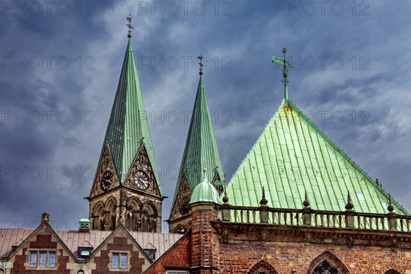 Gothic church towers with green roofs rise against a dramatic cloudy sky, The center of the Hanseatic City of Bremen