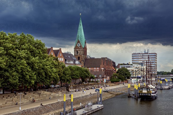 City landscape with a church, its Gothic tower and boats on the waterfront under a cloudy sky, The center of the Hanseatic City of Bremen