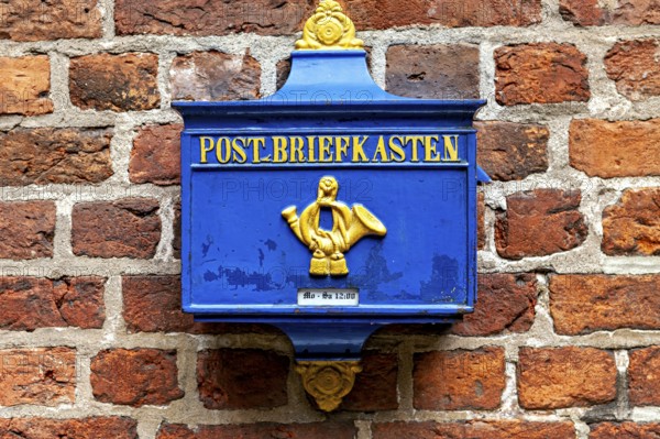 A blue yellow mailbox on a brick wall, nostalgic design, historic blue mailbox