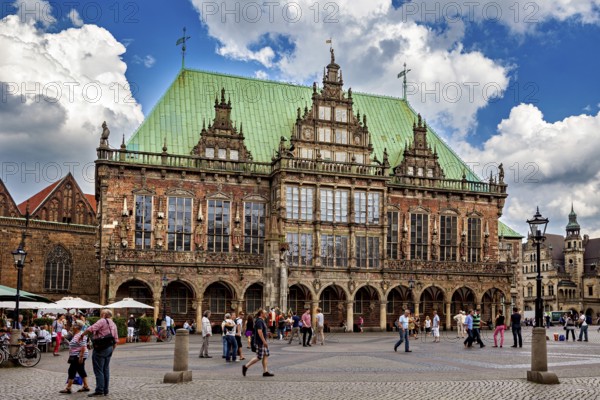 Renaissance town hall with lively hustle and bustle on the paving stone square under a cloud cover, The Bremen City Hall