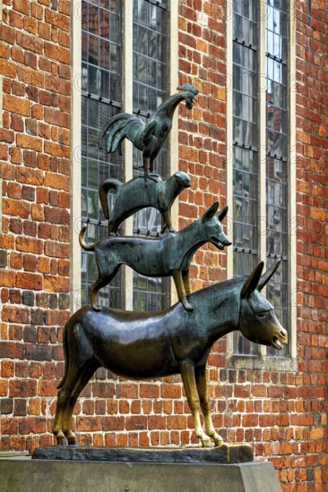 Bronze sculpture of the Bremen Town Musicians in front of a historic brick wall, The Bremen Town Musicians Memorial in Bremen