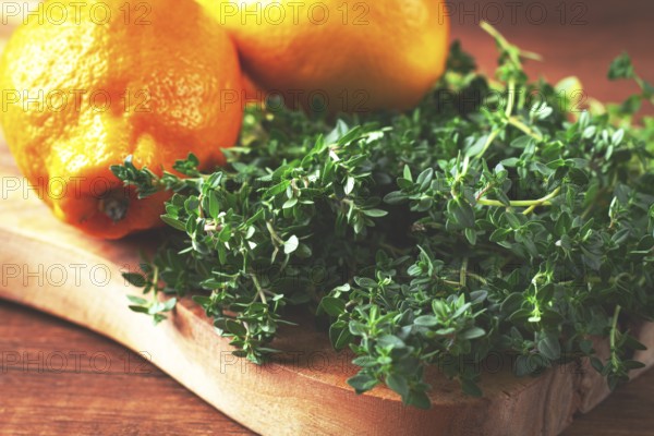 Lemon thyme, on a wooden chopping board, with lemons, close-up