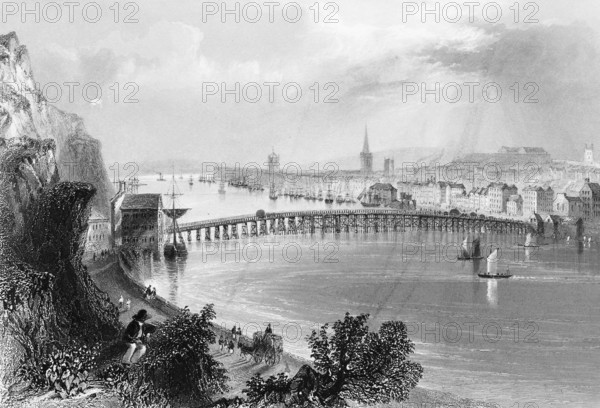 View of the town of Waterford on the Suir River, County Waterford, Ireland, cityscape, architecture, house row, steeple, sailboats, transportation, walkers, riverbank, steep rocky slope, tree, observer, long bridge, construction, landmark, steel engraving, 19th century, historical illustration from 1845