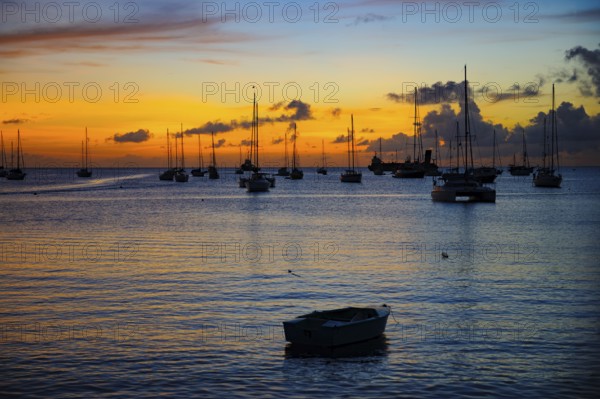 Romantic evening mood over Tyrrell Bay with many sailboats sailing yachts, rowing boat in the foreground, Carriacou, Grenada