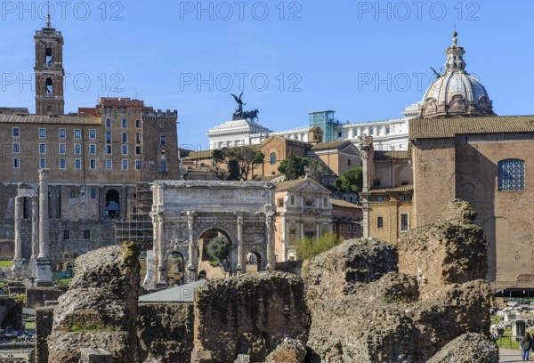 View of Roman Forum, in front ruin of temple of the Divine Caesar Julius Caesar, behind in the middle Severus Arch triumphal arch of Severus, right next to former state prison Carcer Tullianus, left back administration building of Rome Tabularium on Capitol Hill, on the edge of the picture right part of the Curia Iulia Assembly Building, in the middle back on the horizon roof terrace of the National Monument to King Victor Emmanuel II Vittoriano Altare della Patria, Parco archeologico del Colosseo, Rome, Lazio, Italy