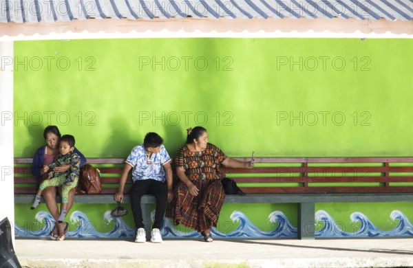 Guatemalans wait at the boat dock in Livingston on the Rio Dulce River, Izabal Department, Guatemala