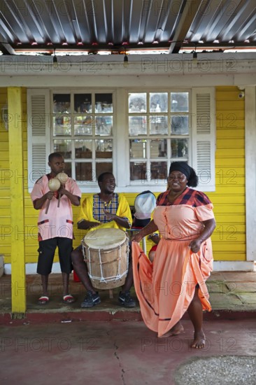 Guatemalan woman in traditional dress singing and dancing, men playing music in the back, Garifuna people, Livingston, Izabal Department, Guatemala