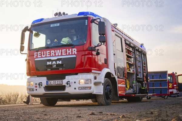 A fire engine with an open equipment door on a street in the morning light, ready to be deployed, fire department exercise on the Hermann Hesse Railway, Ostelsheim, Calw district, Germany