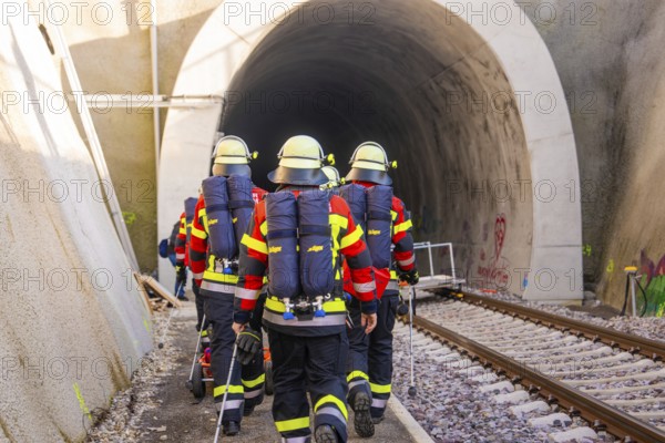Firefighters in protective clothing enter a rail tunnel for a mission, fire brigade exercise on the Hermann Hesse Railway, Ostelsheim, Calw district, Germany
