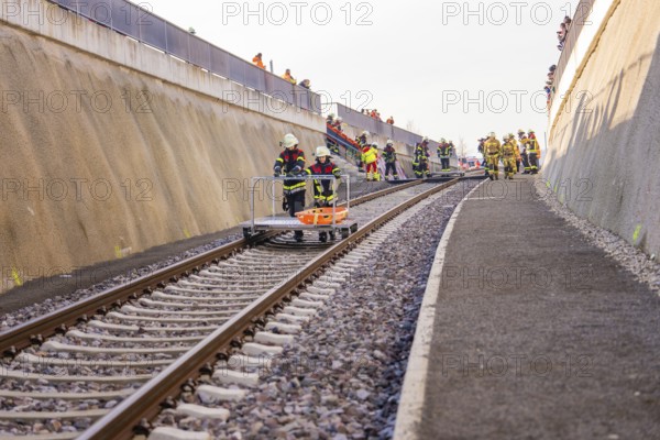 Firefighters work on the rails in a steep area surrounded by sandy walls, fire brigade exercise on the Hermann Hesse Railway, Ostelsheim, Calw district, Germany