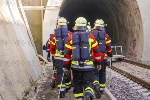Group of firefighters wearing protective clothing enter a dark tunnel, fire brigade exercise on the Hermann Hesse Railway, Ostelsheim, Calw district, Germany