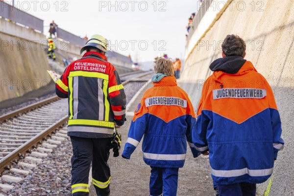 Firefighters in blue and orange uniforms walk along a railway line, fire department practice at the Hermann Hesse Railway, Ostelsheim, Calw district, Germany