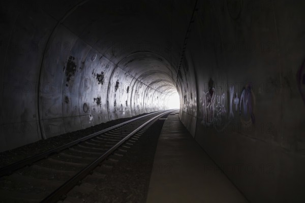 Dark tunnel with railroad tracks, graffiti and a light in the distance, fire brigade exercise on the Hermann Hesse Railway, Ostelsheim, Calw district, Germany