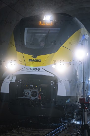 Yellow train travels through an illuminated tunnel on dark tracks, fire department exercise on the Hermann Hesse Railway, Ostelsheim, Germany
