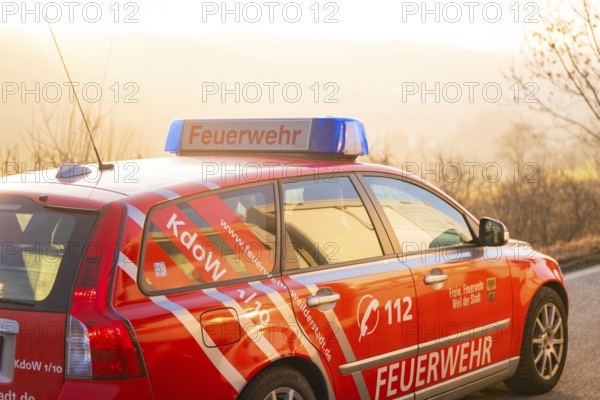 A red fire department car on a country road at sunset, fire department exercise on the Hermann Hesse railway, Ostelsheim, Germany