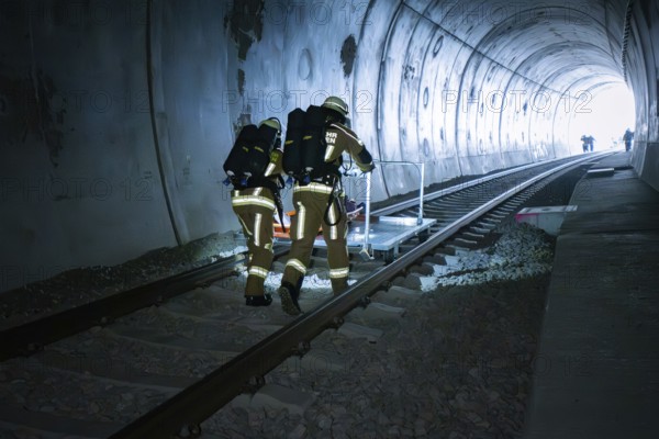 Firefighters move along the rails in the tunnel with equipment, fire brigade exercise on the Hermann Hesse railway, Ostelsheim, Germany