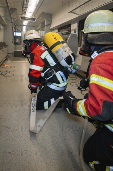 Two firefighters prepare a hose in the interior of a train, fire department exercise on the Hermann Hesse Railway, Ostelsheim, Germany