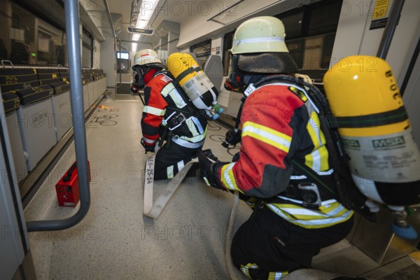 Firefighters move through a train with hoses, fire brigade exercise on the Hermann Hesse railway, Ostelsheim, Germany