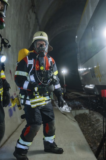 Firefighter standing in a tunnel near a train, equipped for deployment, fire brigade exercise on the Hermann Hesse railway, Ostelsheim, Germany