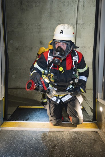 A firefighter wearing respiratory protection kneels in a tunnel at the threshold of a door, fire brigade exercise on the Hermann Hesse railway, Ostelsheim, Germany