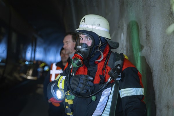 Firefighter wearing respiratory protection in a tunnel surrounded by other rescue workers, fire brigade exercise on the Hermann Hesse railway, Ostelsheim, Germany
