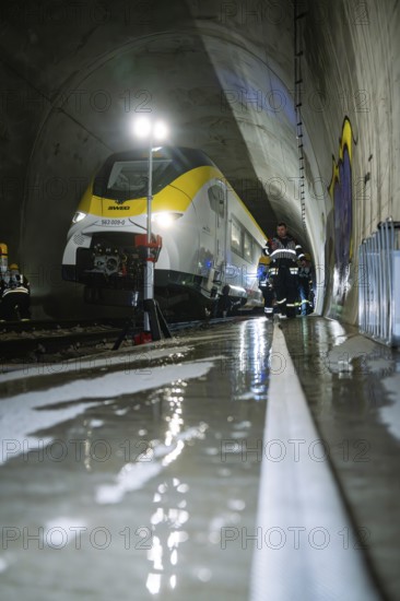 A train in a tunnel surrounded by firefighters on wet ground during rescue work, fire brigade exercise on the Hermann Hesse railway, Ostelsheim, Germany