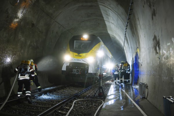 Firefighters during an emergency operation in a dark train tunnel next to a stationary train, fire brigade exercise on the Hermann Hesse Railway, Ostelsheim, Germany
