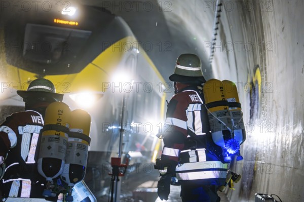 Firefighters wearing respiratory protection against a yellow train in a tunnel, fire brigade exercise on the Hermann Hesse railway, Ostelsheim, Germany