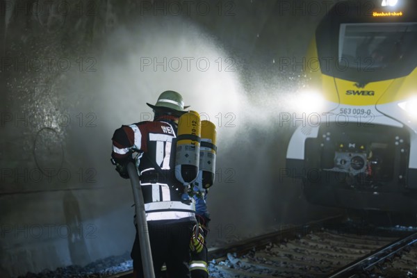 Firefighter with hose and respirator in front of a train in a tunnel, fire department exercise on the Hermann Hesse railway, Ostelsheim, Germany
