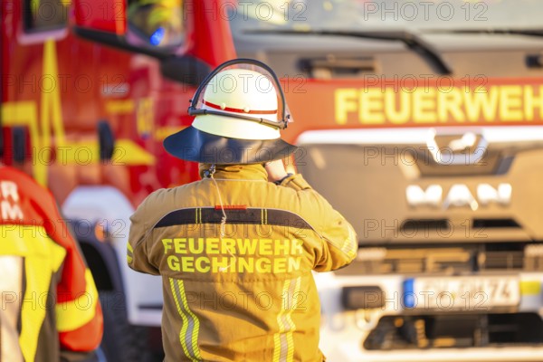 A firefighter stands in front of a fire truck wearing protective clothing, fire department exercise on the Hermann Hesse railway, Ostelsheim, Germany