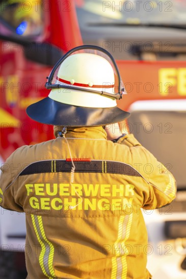 A firefighter stands in front of a fire truck wearing protective clothing, fire department exercise on the Hermann Hesse railway, Ostelsheim, Germany