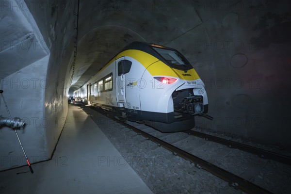 A brightly lit yellow-black train stands in a dark tunnel, fire department exercise on the Hermann Hesse Railway, Ostelsheim, Germany