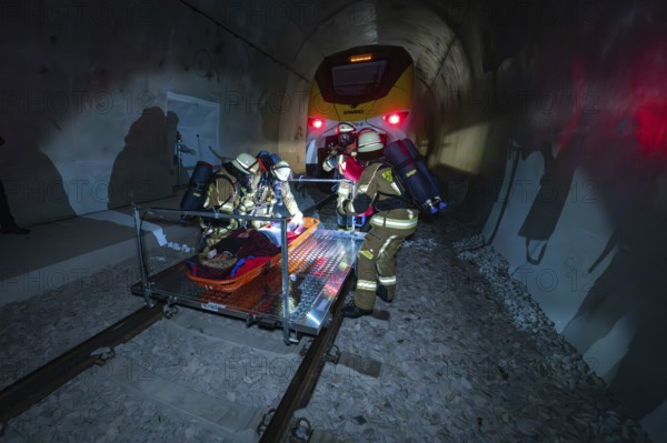 Firefighters work in an illuminated tunnel during a rescue operation, fire brigade exercise on the Hermann Hesse railway, Ostelsheim, Germany
