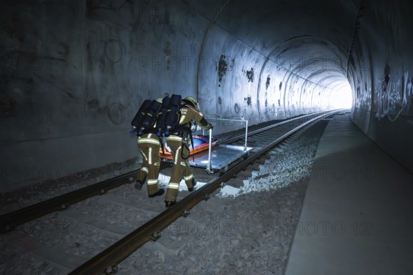 Two firefighters push a stretcher through a dark tunnel, fire brigade exercise on the Hermann Hesse Railway, Ostelsheim, Germany