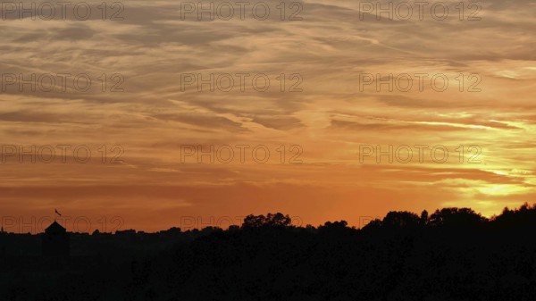 Beautiful sunset with orange sky over silhouettes of trees, Frankenwald nature park Park