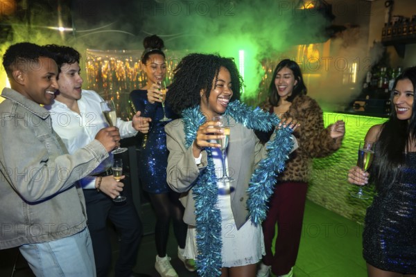 Group of diverse young adults having fun, dancing, and laughing while holding champagne flutes at a vibrant night club or bar, celebrating a special occasion with festive lights and smoke