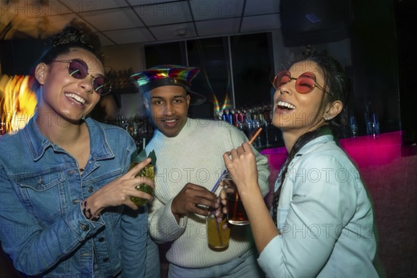 Diverse group of young people socializing at a bar, laughing and holding cocktails under colorful lights, capturing the fun and excitement of a night out